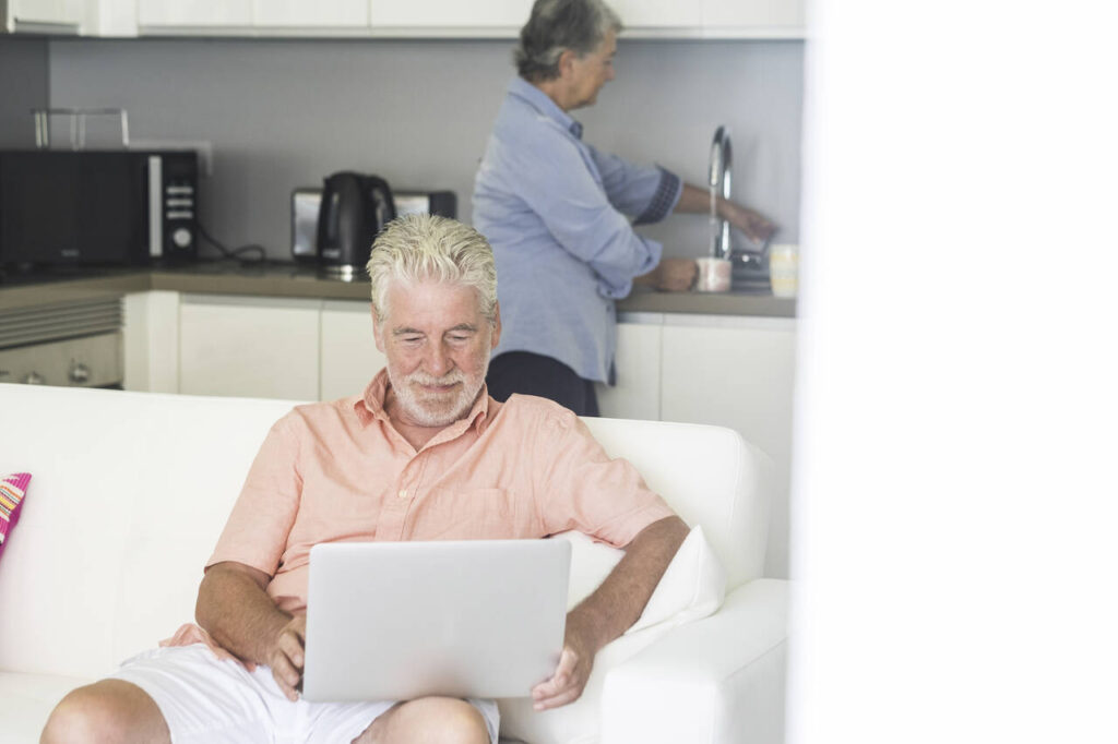Elderly lifestyle people at home enjoying kitchen and desktop laptop computer - coronavirus lockdown quarantine emergency for old senior couple living in city apartment